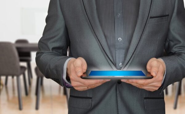 Zakelijke persoon in pak houdt een tablet vast in een vergaderruimte